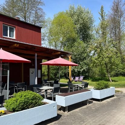 Terrasse mit roten Sonnenschirmen vor dem Café